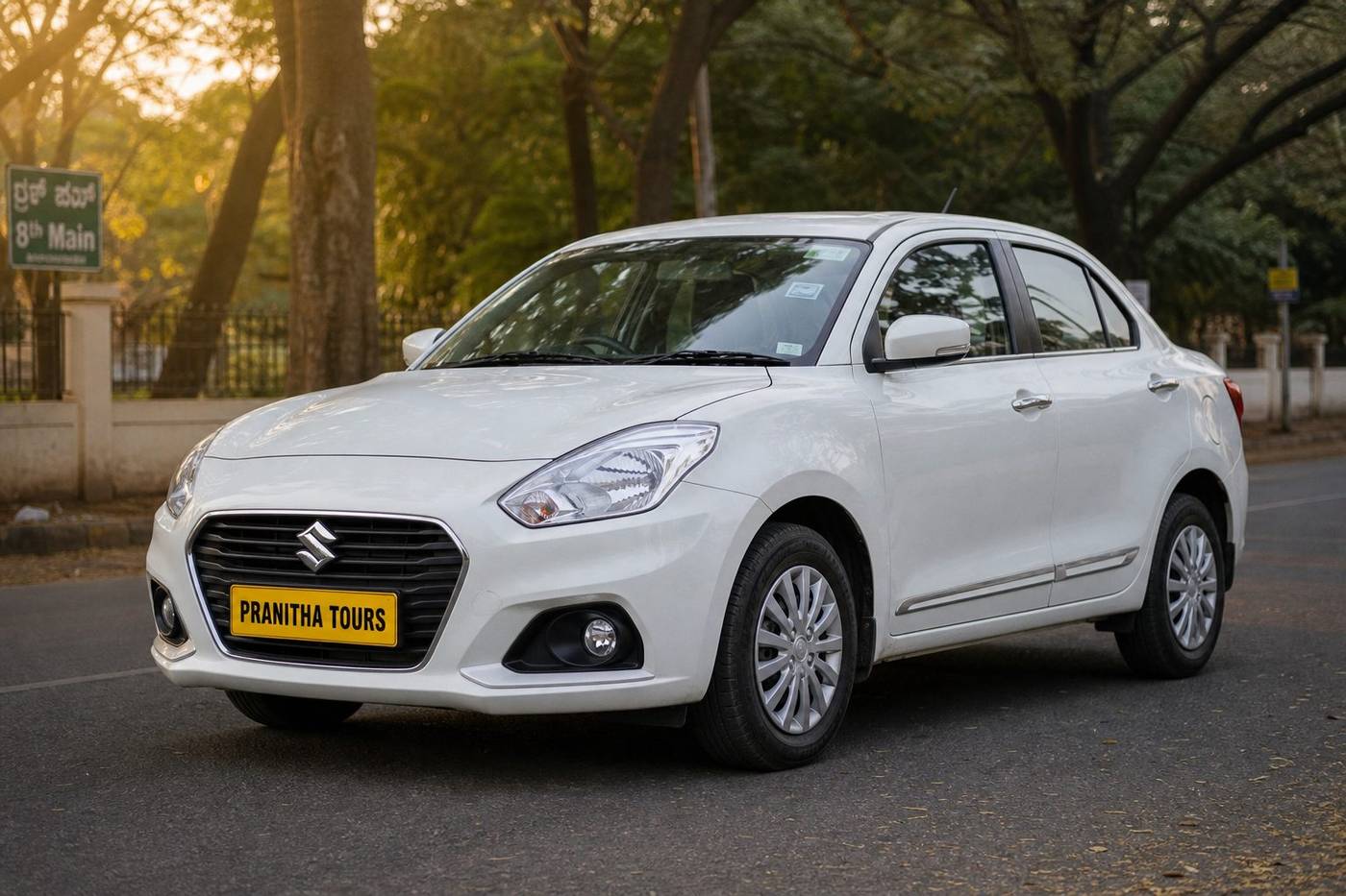 Maruti Swift Dzire sedan with Pranitha Tours yellow plate on a Bengaluru street