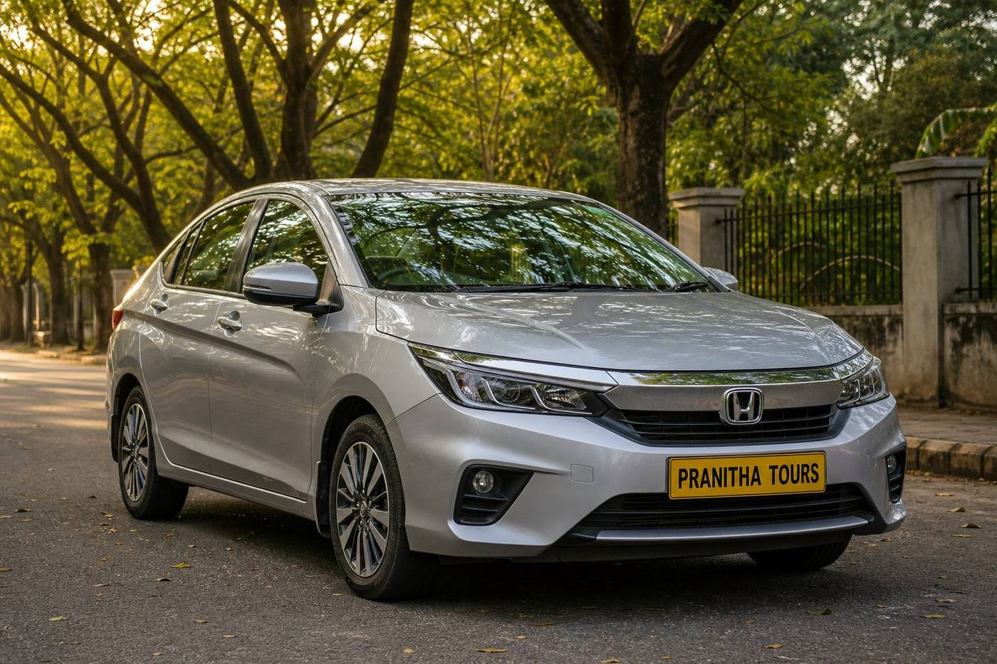 Honda City sedan with Pranitha Tours yellow plate near a Bengaluru tech park